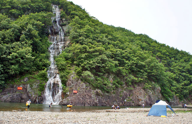 동창천 전경 - 시원하게 떨어지는 폭포 아래 물놀이 중인 사람들