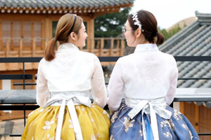 한옥을 배경으로 한복을 입고 서로를 바라보는 여성두명의 뒷모습