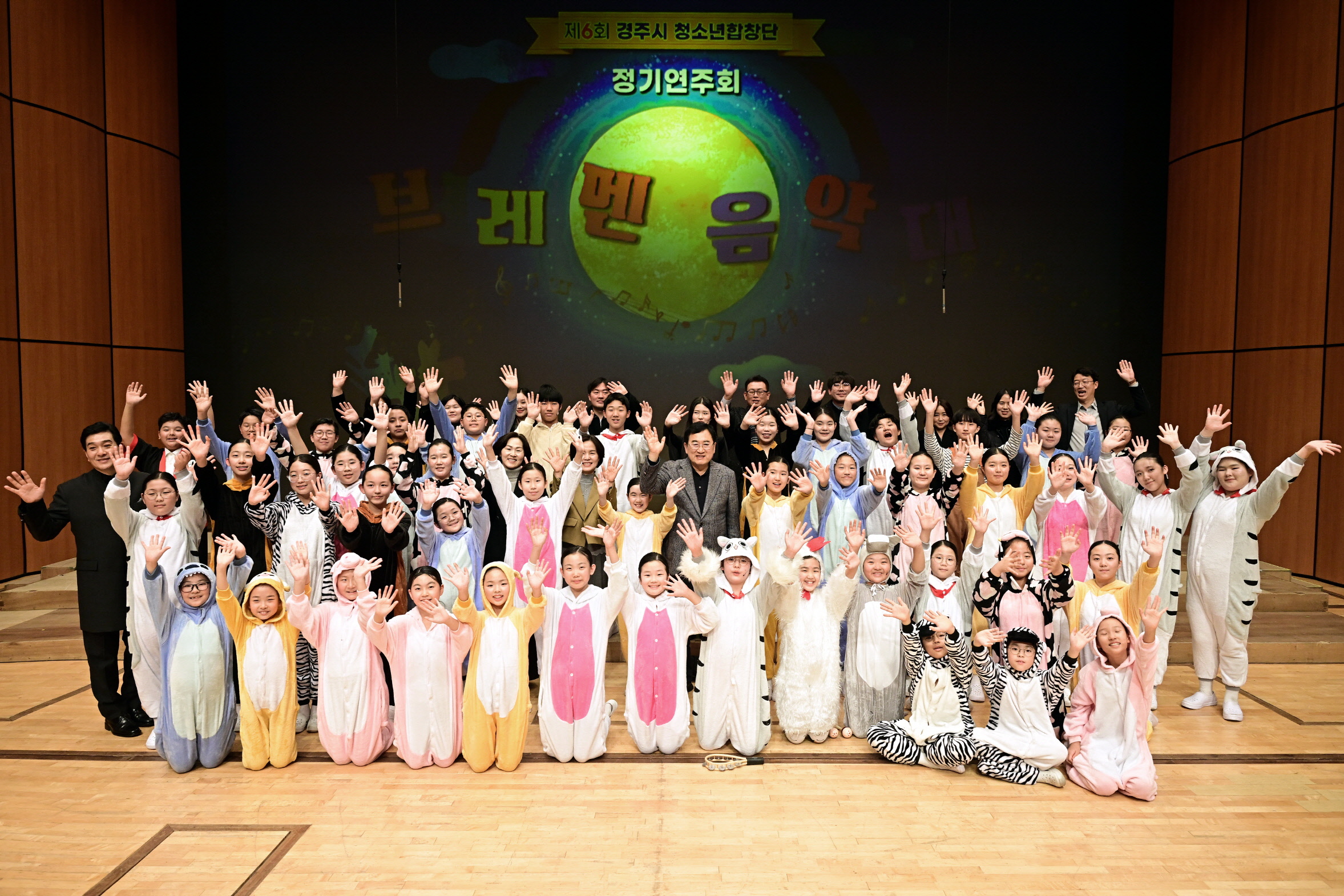 제6회 경주시 청소년합창단 정기연주회가 성황리에 마무리된 가운데, 공연을 마친 단원들과 관계자들이 무대 위에서 함께 기념촬영을 하고 있다